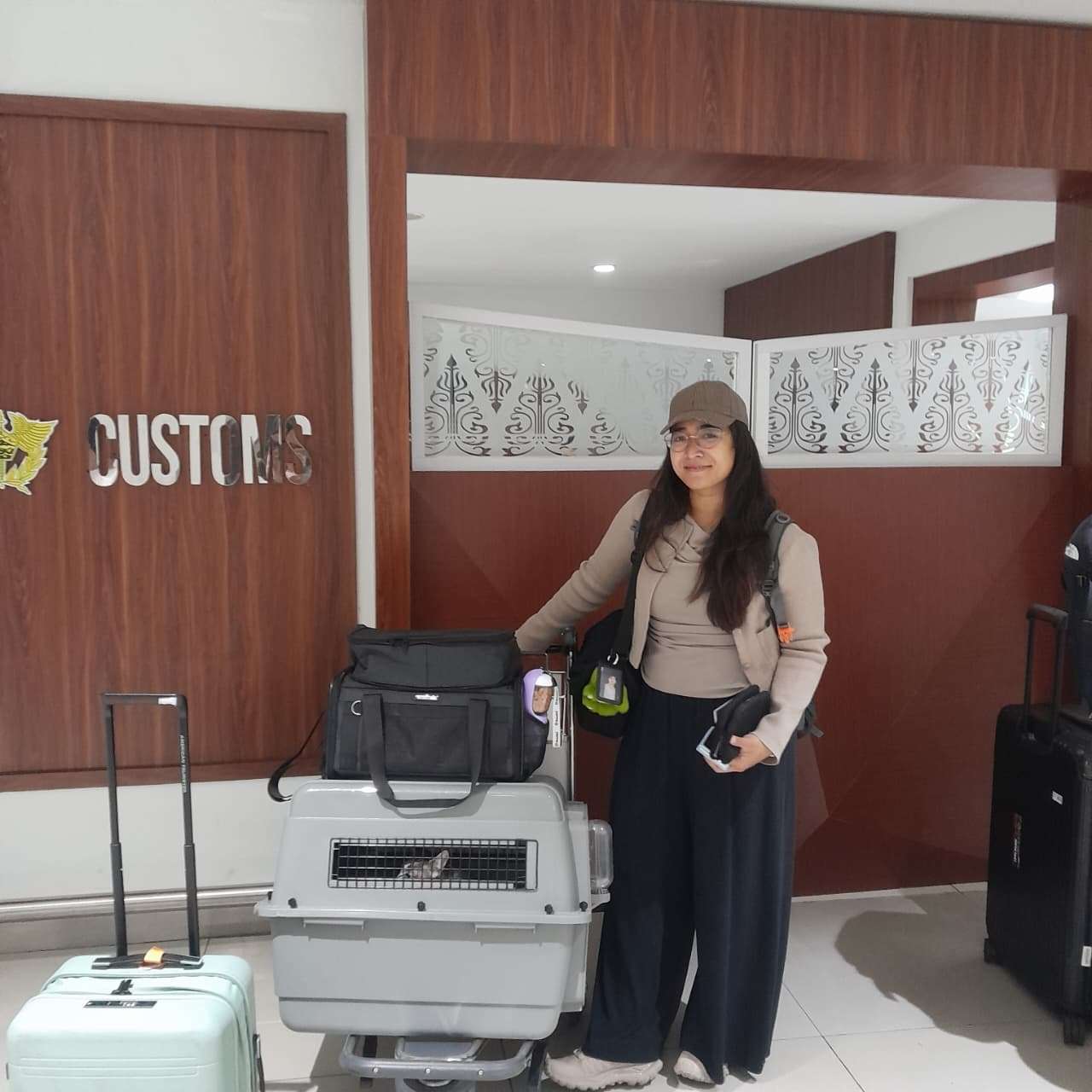 Nabila at Jakarta airport customs beside a travel crate with one of her two cats visible